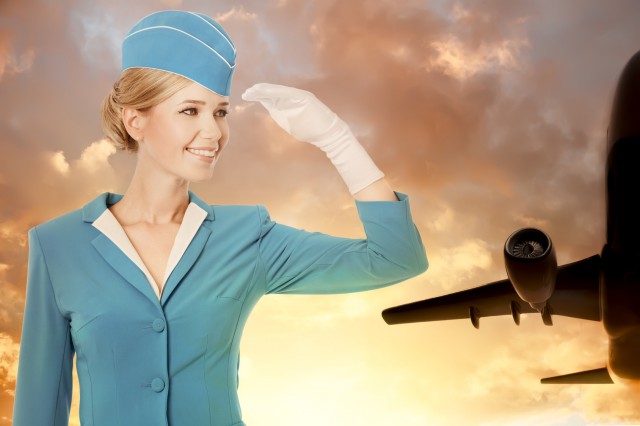 Charming Stewardess Dressed In Blue Uniform On Sky Background