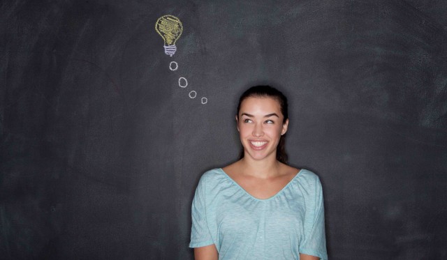 06 Dec 2013 --- Young woman by blackboard with lightbulb --- Image by © David Jakle/Corbis