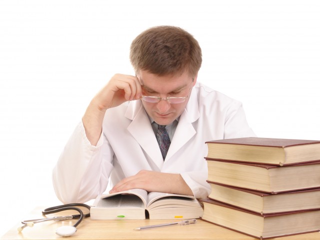 Young male doctor studying medical books - shot over white background