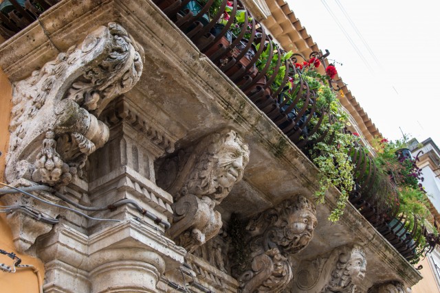 Balcony with iron railing with marble capitals and friezes baroque. Syracuse, Sicily, Italy