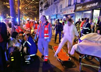 People rest on a bench after being evacuated from the Bataclan theater after a shooting in Paris, Saturday, Nov. 14, 2015. A series of attacks targeting young concert-goers, soccer fans and Parisians enjoying a Friday night out at popular nightspots killed over 100 people in the deadliest violence to strike France since World War II.  (ANSA/AP Photo/Thibault Camus)