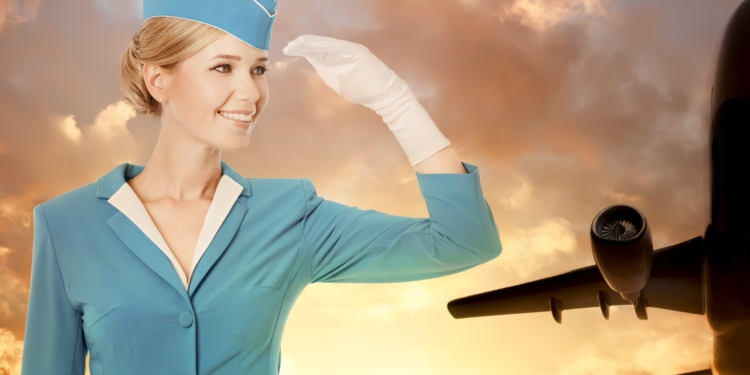 charming stewardess dressed in blue uniform on sky background