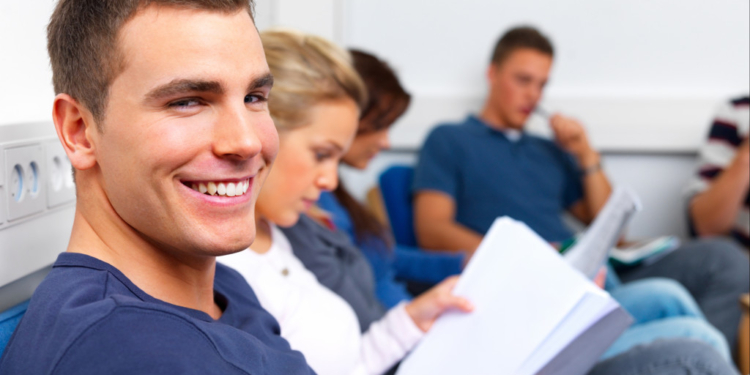 happy young man sitting in class reading