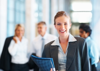 Happy young business woman, colleagues in the background