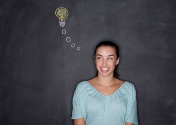 06 Dec 2013 --- Young woman by blackboard with lightbulb --- Image by © David Jakle/Corbis