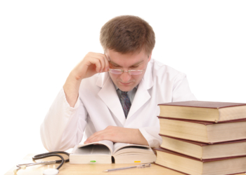 Young male doctor studying medical books - shot over white background