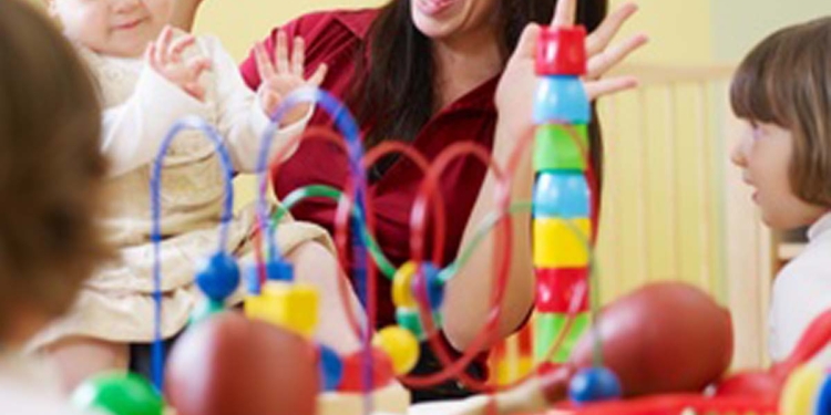 three little girls and female teacher in kindergarten