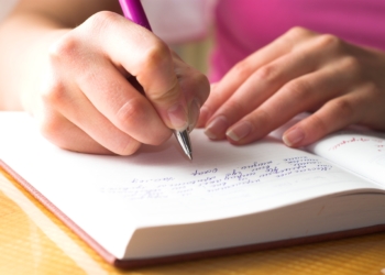 Young female is writing notes and planning her schedule.