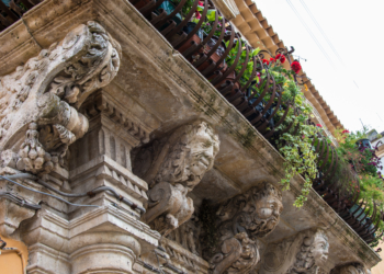 Balcony with iron railing with marble capitals and friezes baroque. Syracuse, Sicily, Italy