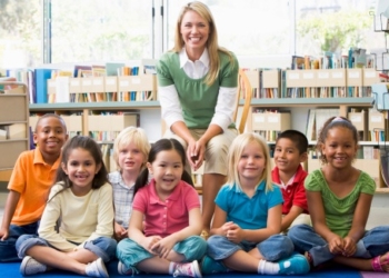 Kindergarten teacher sitting with children in library