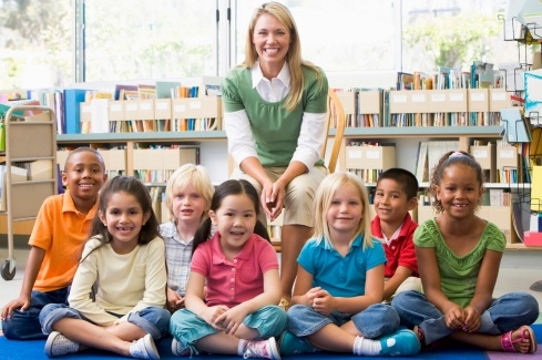 kindergarten teacher sitting with children in library