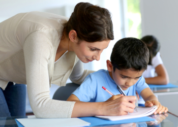 Teacher helping young boy with writing lesson