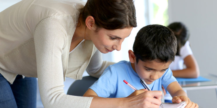 teacher helping young boy with writing lesson