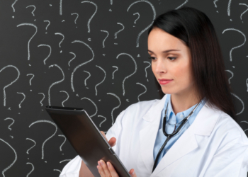 Female doctor with digital tablet in front of question marks on blackboard