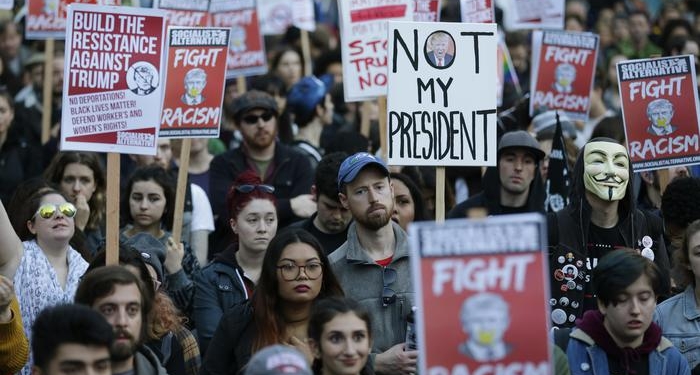 People hold signs as they listen to speakers at a protest against the election of President-elect Donald Trump, Wednesday, Nov. 9, 2016, in downtown Seattle. (ANSA/AP Photo/Ted S. Warren) [CopyrightNotice: Copyright 2016 The Associated Press. All rights reserved.]