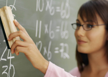 Teacher cleaning chalkboard with duster --- Image by © Royalty-Free/Corbis