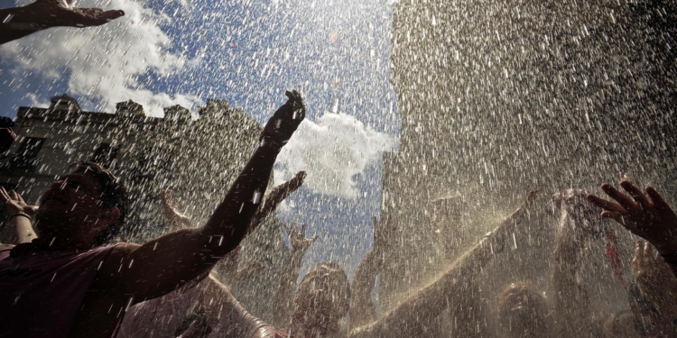Revelers react as water is thrown from a balcony during the 'Chupinazo', the official opening of the San Fermin fiestas in Pamplona, northern Spain, Wednesday, July 6, 2011. The fiestas 'Los San Fermines' held since 1591, attracts tens of thousands of foreign visitors each year for nine days of revelry, morning bull-runs and afternoon bullfights. (AP Photo/Alvaro Barrientos)