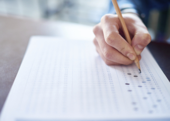 Hand of male student filling out test answer sheet