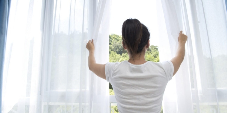 woman opening white see through curtains