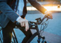 Midsection of businessman commuter with electric bicycle traveling home from work in city.