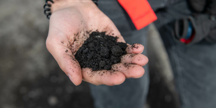 hand holding black volcanic ash