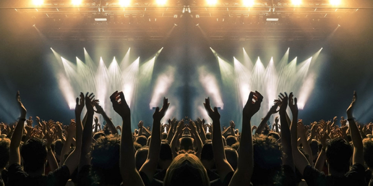 concert stage people are visible waving and clapping silhouettes are visible