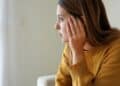 portrait of sad lonely girl at home looking through window ment