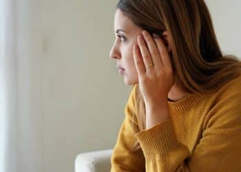 Portrait of sad lonely girl at home looking through window. Mental health, anxiety depressed thinking teenage.