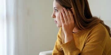 portrait of sad lonely girl at home looking through window ment