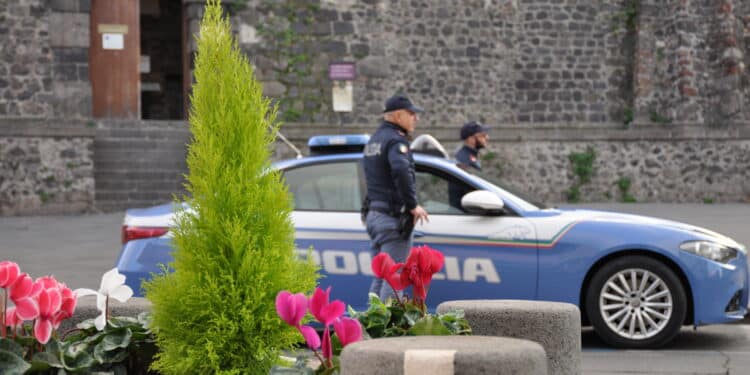 In foto un auto della polizia e due poliziotti